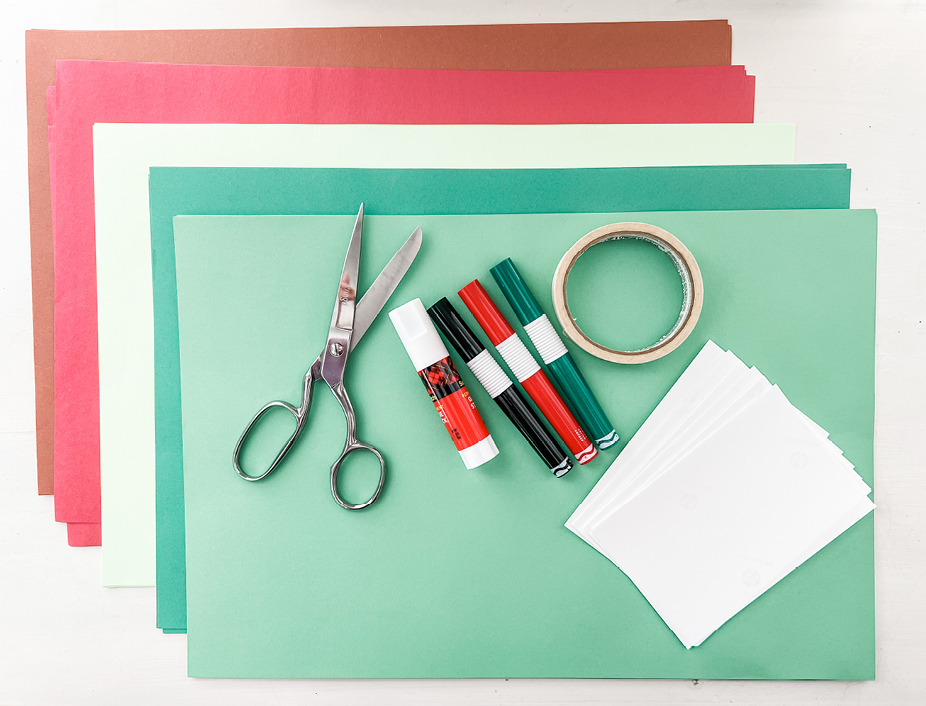 green, white, red and brown construction paper with scissors, markers, a glue stick, and tape